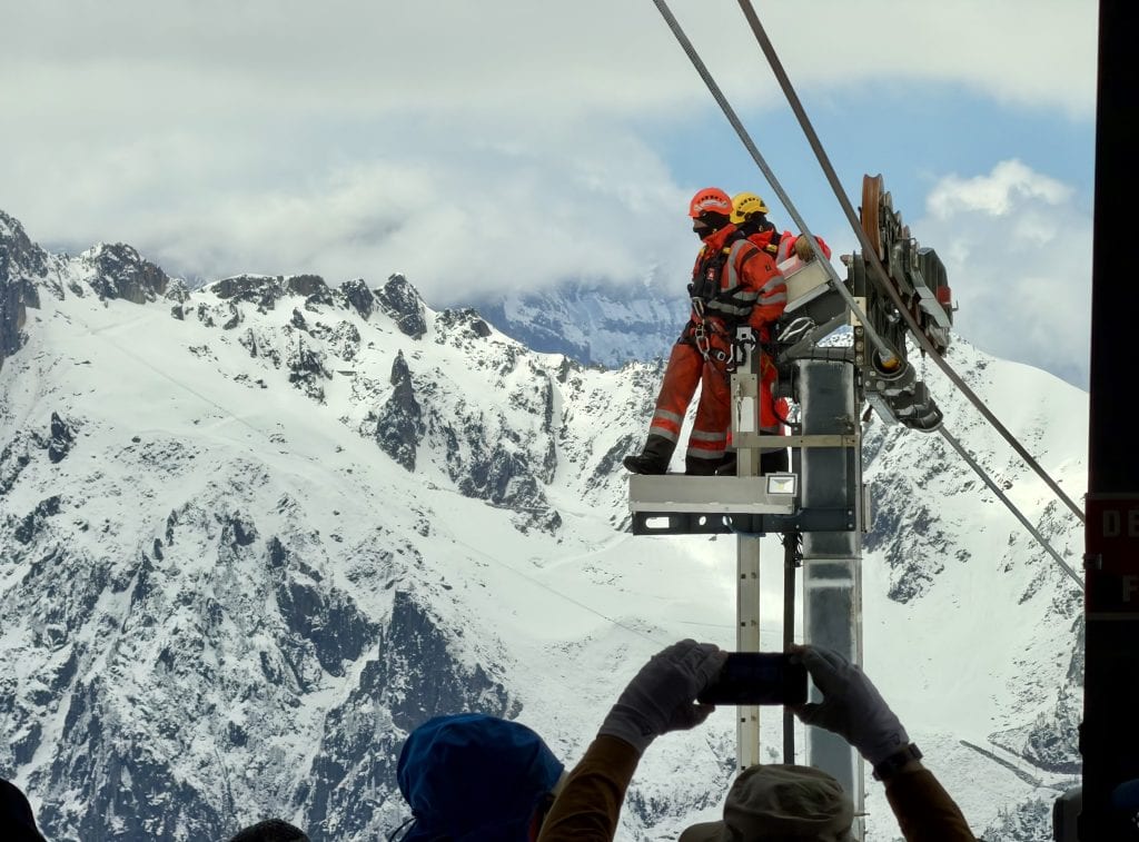 Workers on a platform above the cable car gondola